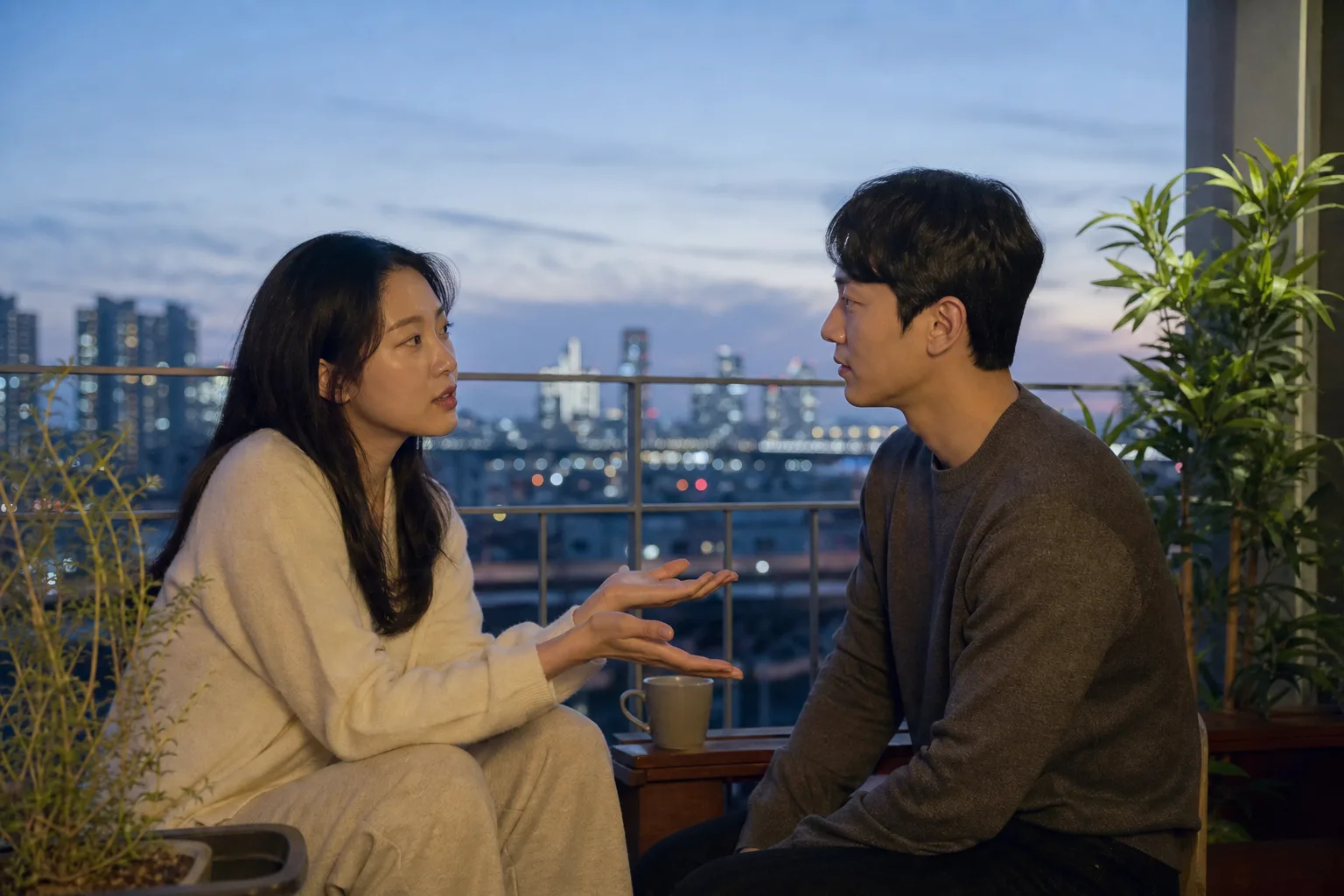 서울 야경이 보이는 창가에서 손을 펴고 안심이 필요하다고 솔직히 말하는 연인의 모습