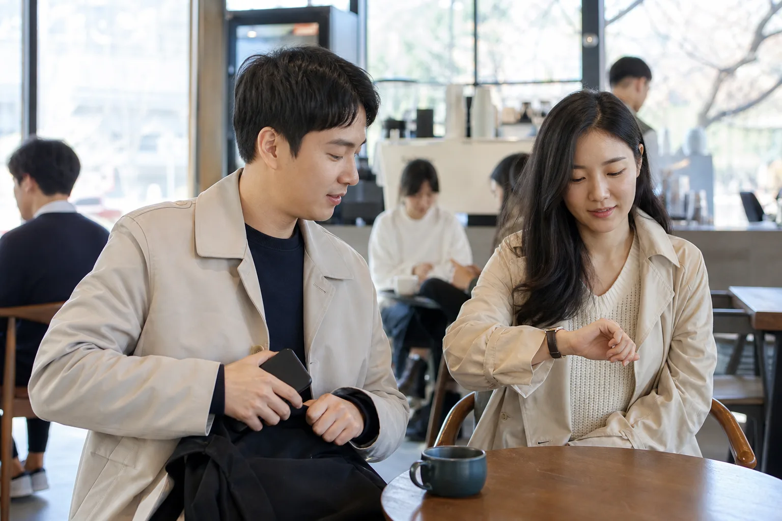 연락 빈도 차이를 손목시계와 휴대전화를 내려놓고 조율하는 연인의 모습
