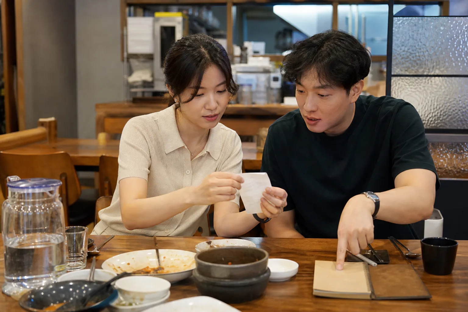 식사 뒤 영수증과 메모를 보며 데이트 비용을 동등하게 논의하는 연인의 모습