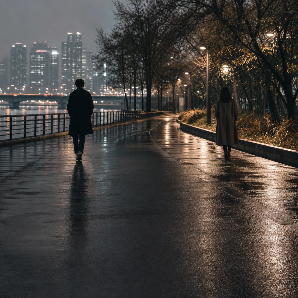 Two people walking in opposite directions along a riverside path after rain